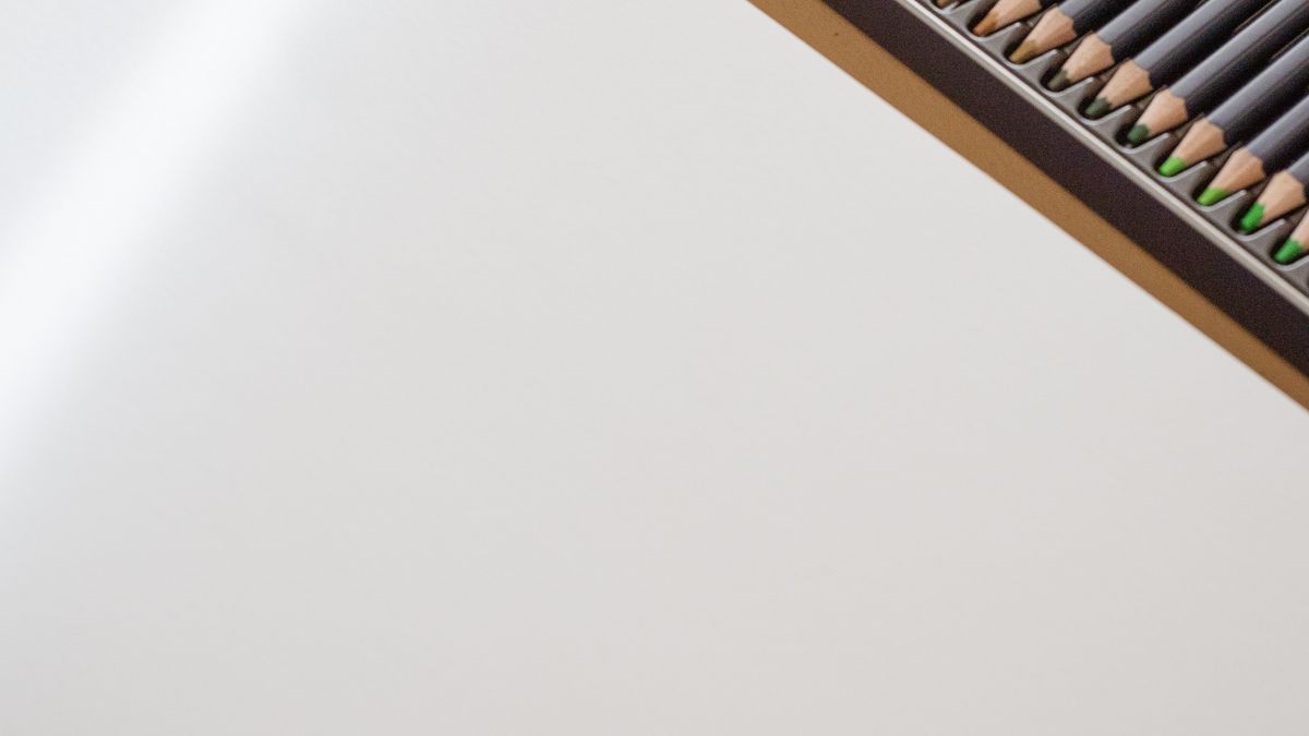A blank spiral sketchbook beside a set of coloured pencils