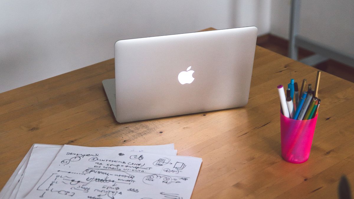 A laptop and papers on a light wooden work table